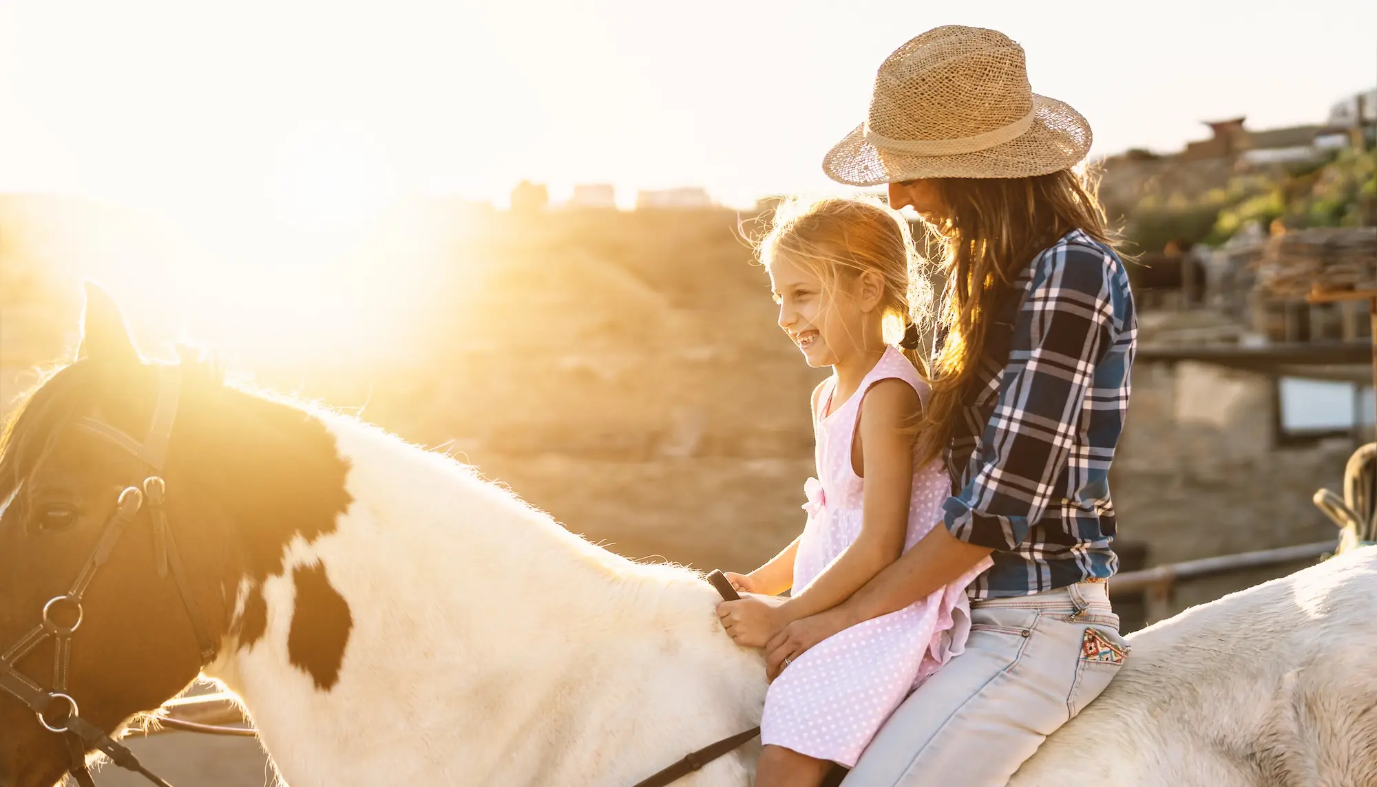 Happy family mother and daughter having fun riding horse inside ranch